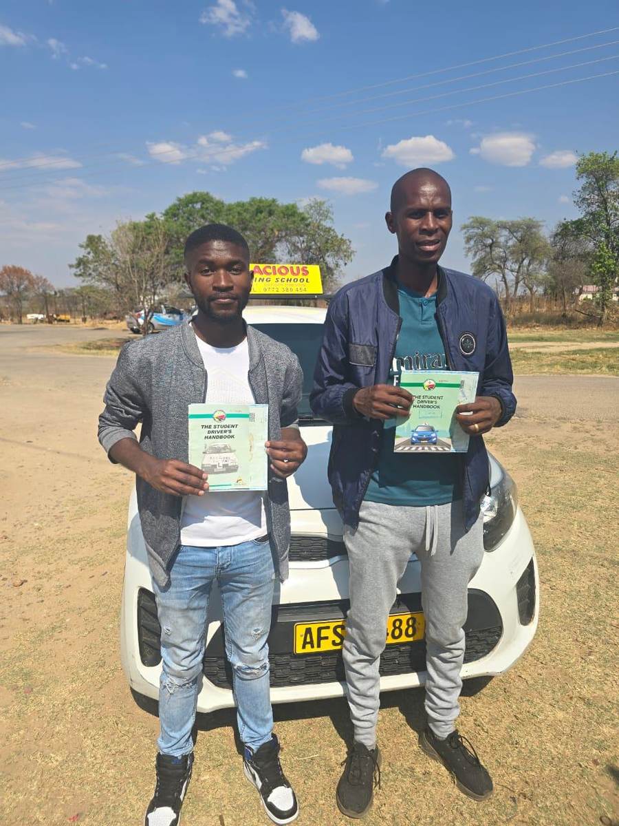 Students holding their Gracious Driving School driver's handbooks